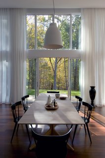 The dining space is directly connected to the outdoors through sliding glass doors and views to the trees beyond. 