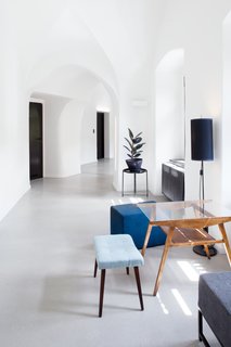 A Stylish Hostel in a Historic Czech Fortress Starts at $16 a Night - Photo 15 of 19 - Midcentury modern furniture pieces with blue pastel upholstery and warm, wood tones accent the bright white corridors. 