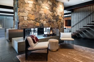 An Award-Winning Midcentury Residence in Los Angeles County Asks $3.9M - Photo 11 of 17 - A two-sided fireplace visually connects the living spaces. Open tread stairs hang from the floor above. 