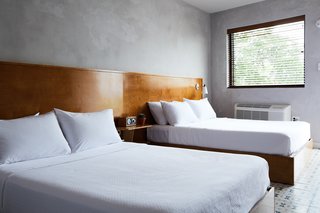 The double queen guest room's minimalist interiors include a custom, double-platform bed, cement tile floors, and troweled concrete walls. 