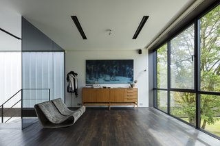 Chairs by Willy Guhl, a cabinet by Pieter De Bruyne, and artwork by Xavier Visa decorate a sitting area on the upper floor, flanking the steel staircase.