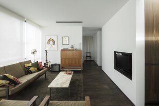 The living space is anchored by a marble coffee table created by Poul Kjaerholm and a wooden cabinet by Pieter De Bruyne.