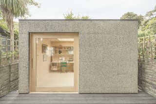 This backyard home office for a couple in London is constructed with all-timber structural framing and is clad in cork and topped with a vegetated roof. These eco-friendly materials make for a delightfully sensory space with lots of lighting provided by the skylight and glass and oak door.