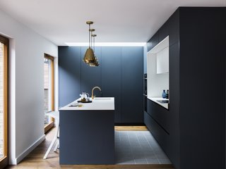 A Sleek Renovation in London Ushers Light Into a Family Home - Photo 7 of 11 - Aston pendants by House Doctor match the metallic hue of the tap. White Miura Stools by PLANK provide seating at the island. 