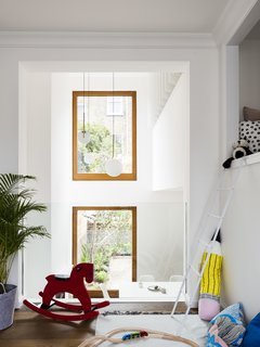 A Sleek Renovation in London Ushers Light Into a Family Home - Photo 4 of 11 - A lofted playroom overlooks the main living space. A seamless piece of glass provides a discrete barrier. 