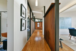 The central gallery, framed by wood screen walls on both sides, links the main living spaces. The partitions create a more open, expansive volume. 