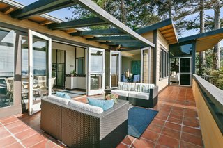 Exterior terraces wrap public living spaces. A wooden pergola shades the exterior sitting space. 