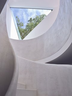 The curvilinear staircase—painted all white—contrasts with the angular forms evident throughout the residence.