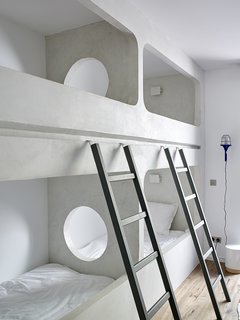 Custom bunk beds are built into one of the guest bedrooms. The circular opening adds a playful, modern touch.
