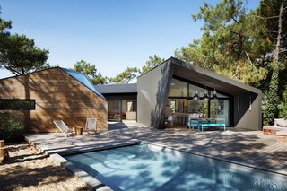 The wood-wrapped exterior blends seamlessly into the forest, making the light and shadows of the neighboring trees play on the textured facade.