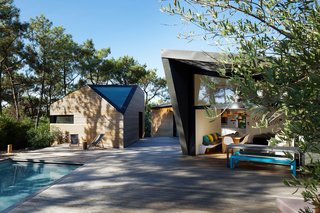 A large wooden terrace connects the various volumes to the pool setting. Large, glass doors connect the kitchen and dining space directly to the outdoor setting.