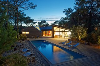 At sunset, the home glows like a shining lantern set within the forest.