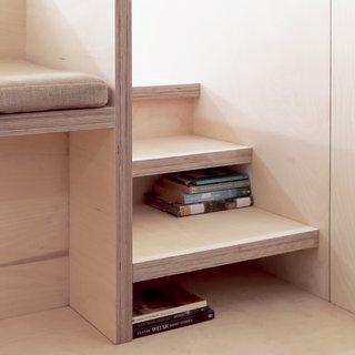 Stairs leading up to the platform bed doubles as storage for books.