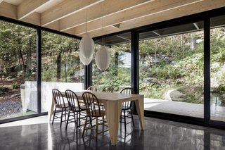 A custom-designed wooden dining table is surrounded by chairs acquired at Saint-Michel Flea Market in Montreal. IKEA pendant lamps decorate the space.