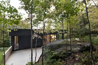 The home appears as if it is carved into the mountainside, serving as one with the trees and rock formations.