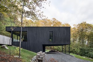 Supported on thin columns, the main volume hovers above the graveled entry, reaching out into the surroundings.