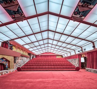 The Music Pavilion is filled with a soft, uniform white light diffused by the canvas roof overhead. Deep red hues echo the warmth of the desert.