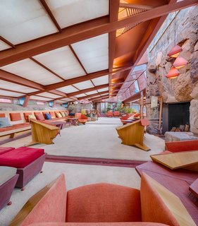 A stone hearth anchors the grand space. Custom Taliesin Wright Chairs were purposefully designed for the human scale and provide a variety of seating options, and are covered in rich velvet textiles.