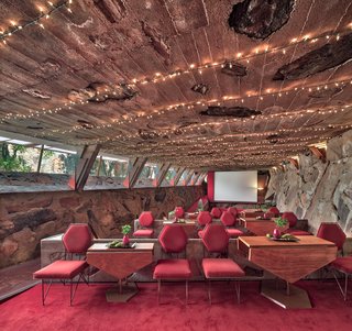 The Cabaret Theater, used for music and theater, displays the thickness of the exterior walls with buttressing structural supports extending to the roof. Bold red chairs and lush red carpet match warm, desert hues.