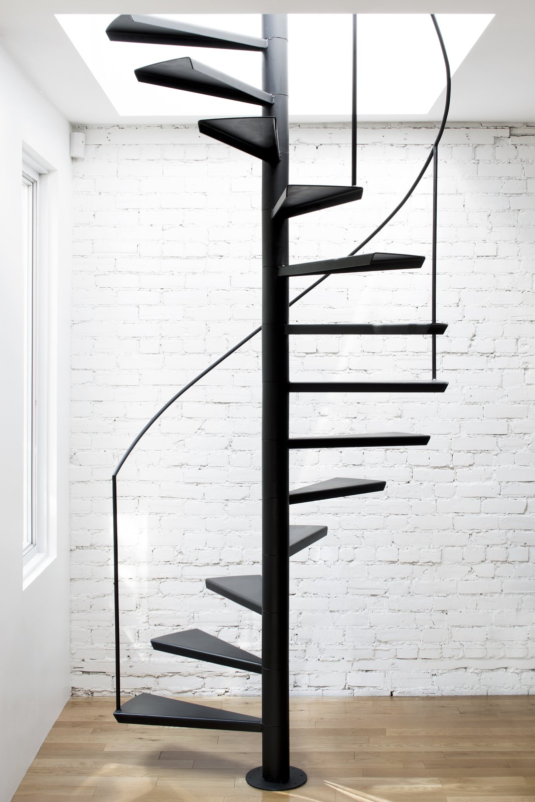 An interior, custom-made steel staircase with floating treads and a minimal handrail, lead to the roof deck above.