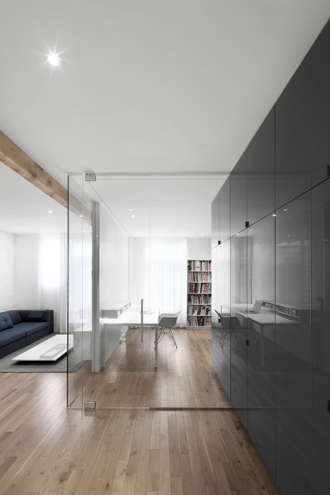 The full height gray cabinets extend into the office space, blurring the boundary between office and kitchen. Seamless glazing further increases the transparency between spaces.