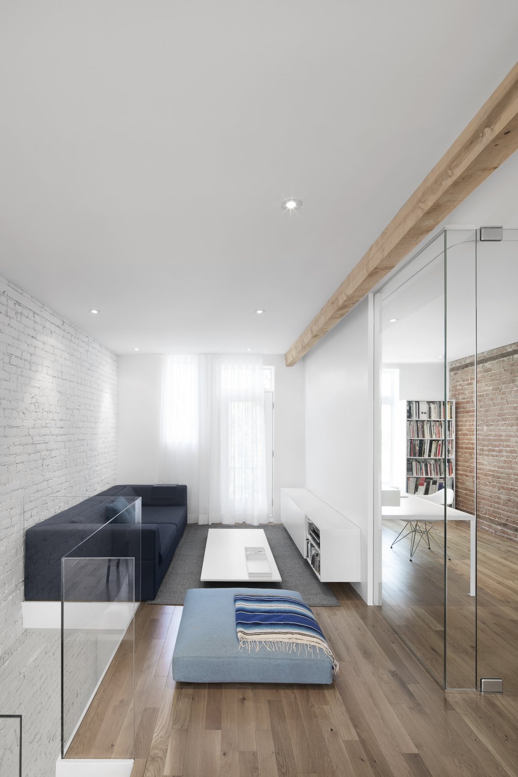 A lounge space, decorated with dark and light blue hues, sits directly atop the entry stairs. A white painted brick wall provides an idea backdrop which extends between spaces.