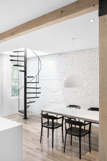 A formal dining space lies adjacent to the kitchen island. A simple, white pendant light hangs above the black and white dining furniture.