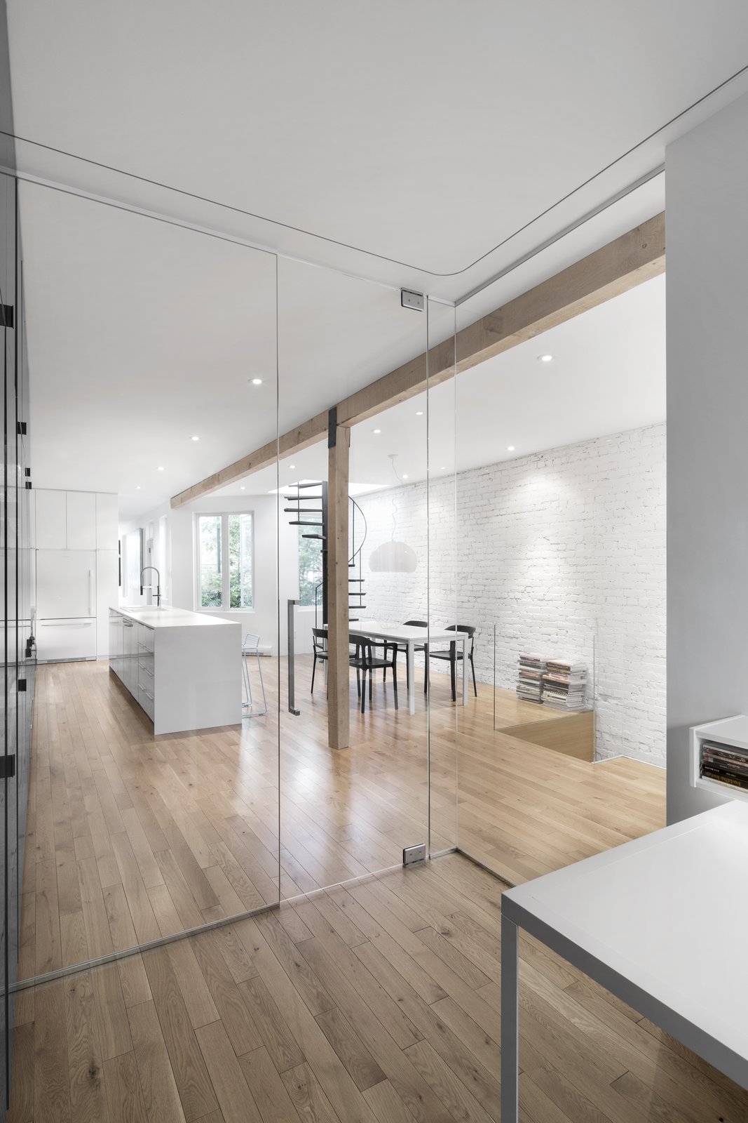 Glass walls allow light to filter through all spaces in the floor plan. Continuous wood flooring blends from room to room, creating a coherent space.