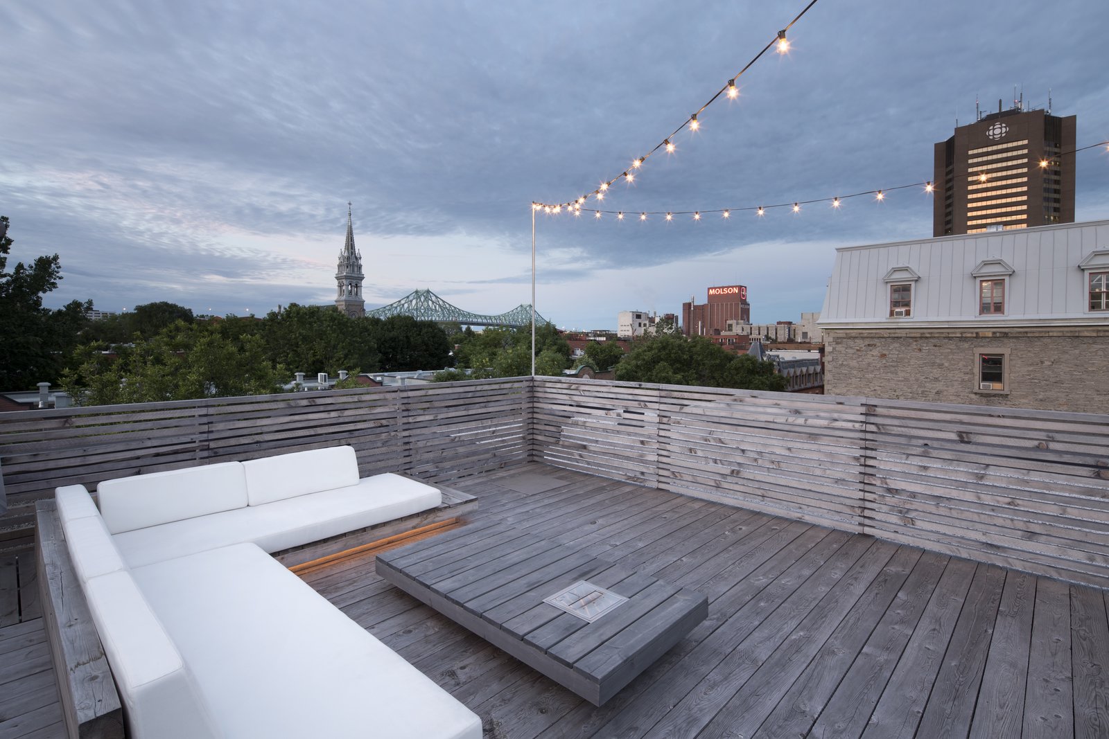 The wood deck roof terrace, complete with ample lounge seating, provides astounding views of the city beyond.