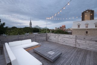 The wood deck roof terrace, complete with ample lounge seating, provides astounding views of the city beyond.