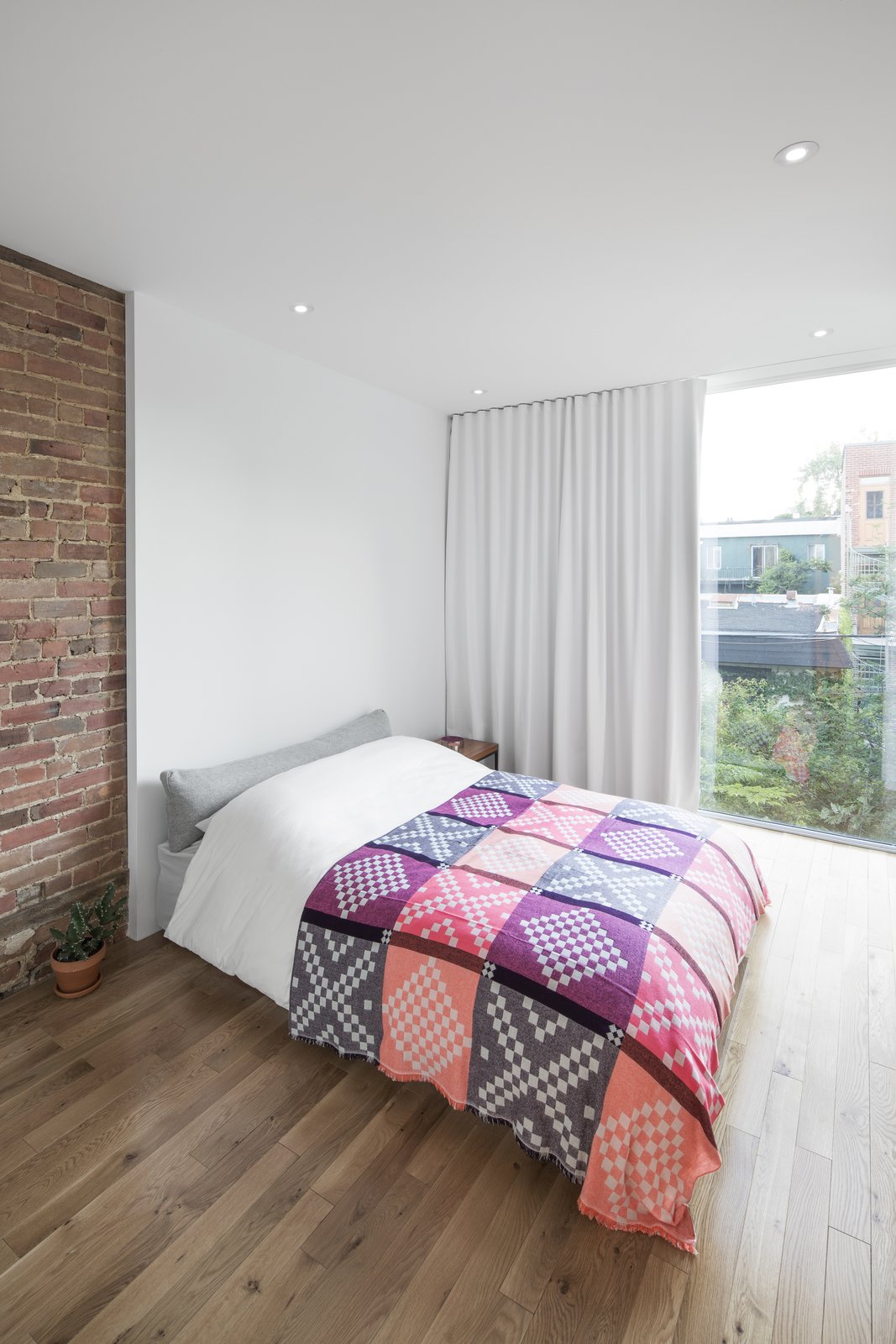 In the bedroom, full height glazing allows natural light to fall deep into the apartment. Elegant, white curtains provide privacy as needed, well matching the surrounding wall colors.