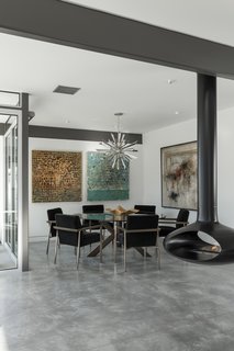 Modern furnishings, a decorative metallic pendant, and colorful artwork decorate the dining space.
