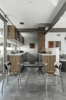 A contemporary galley kitchen with wood cabinetry provides an open, fluid cooking space. The cooktop hood nestles perfectly against the structural framing.