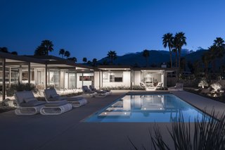 At dusk, the light-colored home glows like a lantern in the desert sky.
