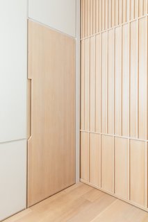 A Steel Staircase Merges Two Units Into One in Tribeca - Photo 5 of 13 - Integrated door pulls omit the need for additional hardware. The wood pocket door is a geometric pattern of linear wood details. The home's finishes are industrial and minimal, balancing with the exposed wood structure throughout the unit.