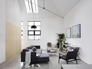 A large living space combines the best of all elements: exposed cable trusses, steel framed windows, wood accents, polished concrete floors, mod finishings, and a simple pendant light. 