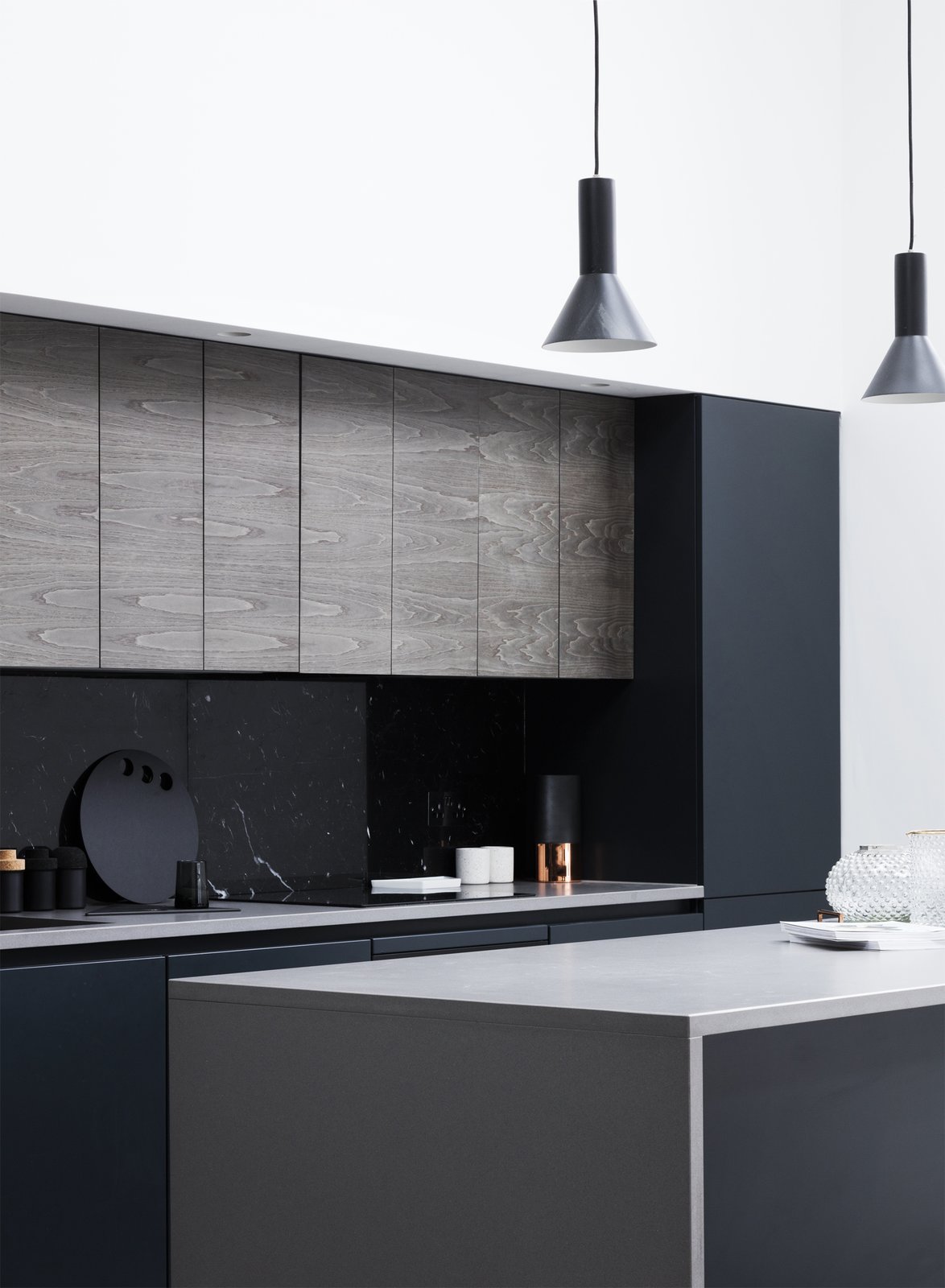 A black marble back splashed and matched oak veneer door fronts contrast with the white walls and light wood panels throughout the home. Flat panel cabinets add an extra modern flair.