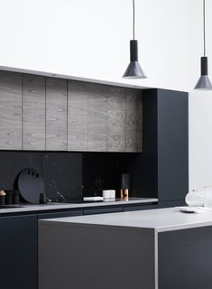 A black marble backsplash contrasts effortlessly with the white walls and light wood panels throughout the home. Flat panel cabinets add an extra modern flair.