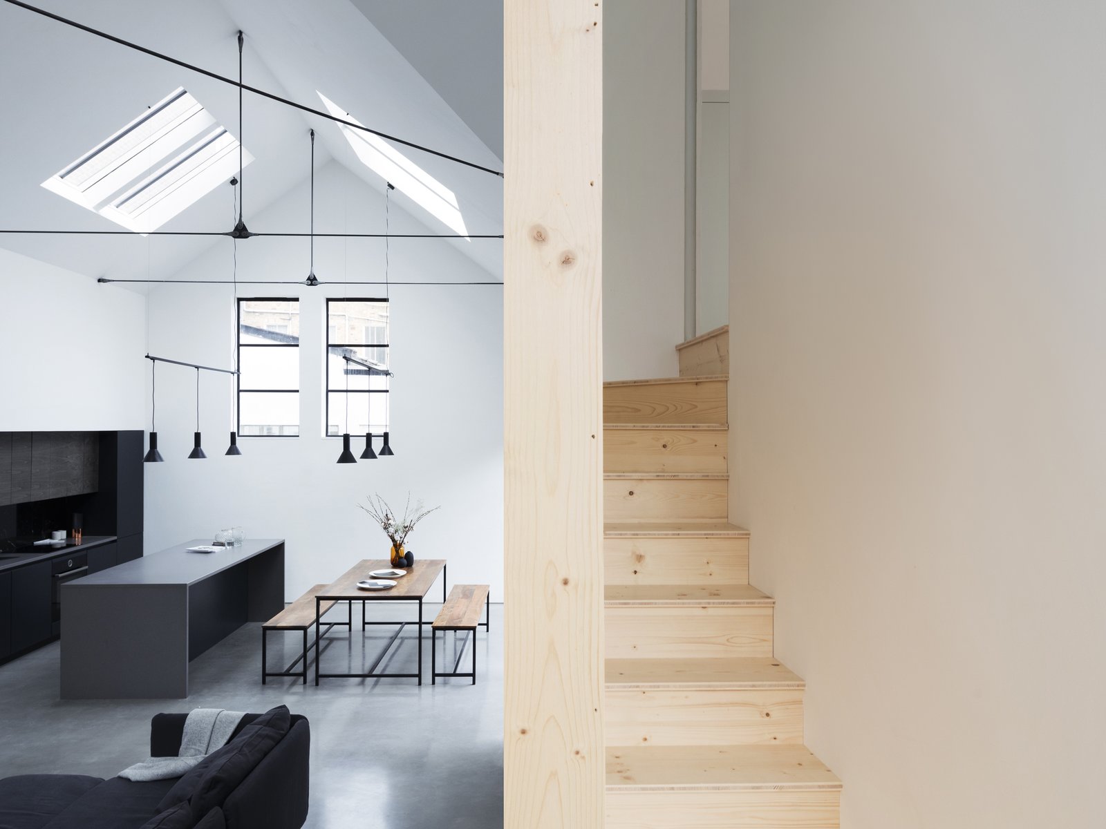 The wooden staircase winds its way between the main living space and the sleeping spaces above.