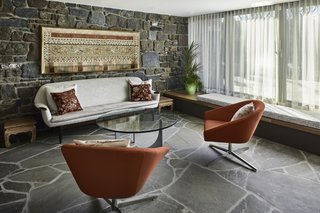 The exterior stone wall, which carries through into the interior, and the fieldstone floors draw nature inside. A custom, built-in window seat anchors the sitting room.