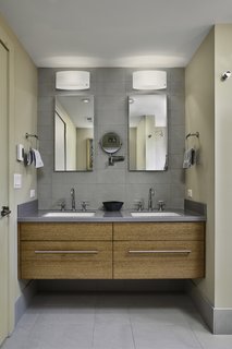 The guest bath includes a custom vanity complete with Kohler fixtures and a Corian countertop. Atlas Concorde porcelain tiles decorate the sink wall and bath floors.