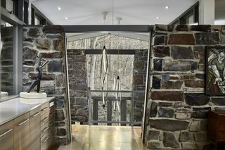 The view from the addition looks outward. A decorative pendant, In The Wind Vertical from Nemo Lighting, hangs above the entry way.