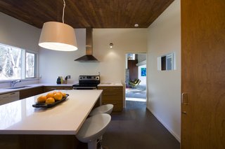 The central kitchen is strategically placed for views throughout the home. Large windows above the sink connect it to the garden lot.