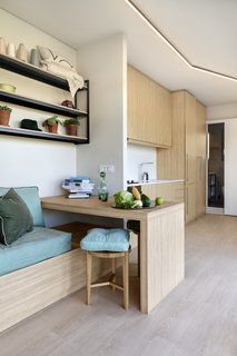 The same light, rift-cut wood is used throughout the space, creating a continuous connection between spaces. The built-in table can be used as a desk or dining area.