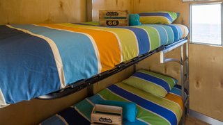 The truck contains four bunk rooms, each with a small window looking out onto the ocean.