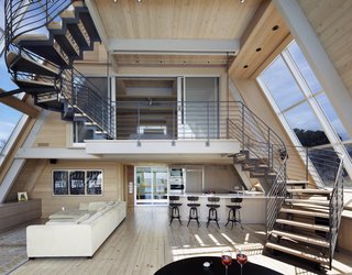 The open kitchen gently tucks under the upper floors and the wood and metal stair that delicately weaves its way upward. The large bay windows draw daylight in from both sides.