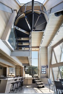 The staircase is a sculptural solution composed of wood treads, steel supports, and a steel guardrail that winds its way upward.