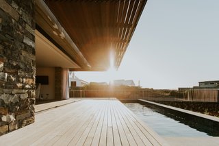 The wood canopy and the wood deck align in extension, framing views of the neighborhood beyond.