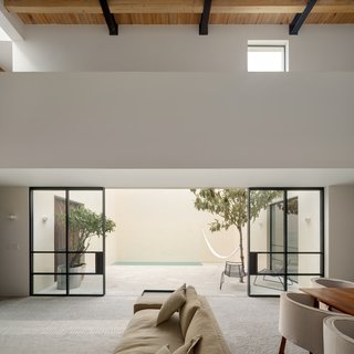Sliding glass doors provide a seamless connection between the interior and outdoor spaces. Green vegetation dots the courtyard, drawing the colors of nature inward.