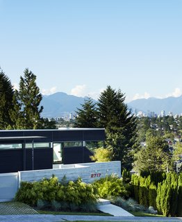 Upon entry, the cascading form of the home is minimized. In view, is a board-formed concrete wall and a south-facing garden, with harbor views in the background.